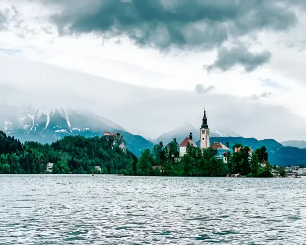 Jezioro Bled ze słynną wyspą i kościołem to obowiązkowy punkt, co warto zobaczyć w Słowenii. W tle góry.