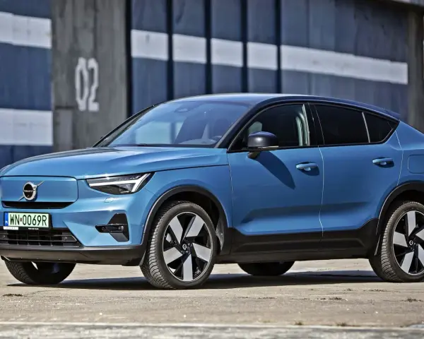 Niebieskie Volvo C40, elektryczny SUV coupe, parkuje przed budynkiem z numerem "02".