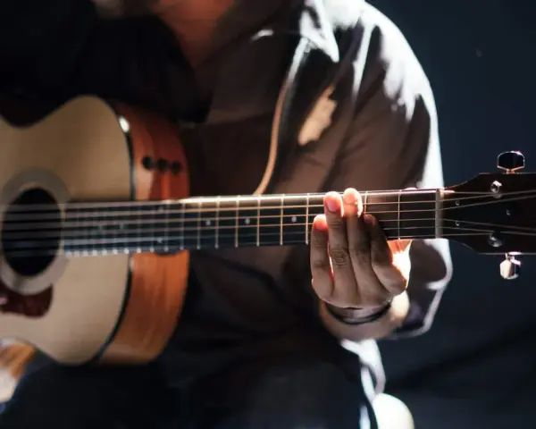 Gitarrist übt den **palm mute**-Effekt auf einer Akustikgitarre, die Finger liegen auf den Saiten.