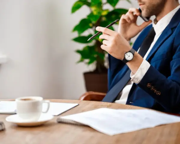 Biznesmen rozmawia przez telefon, trzymając długopis. Na stole kawa i dokumenty. Pytanie: na ile rat sąd może rozłożyć zadłużenie?