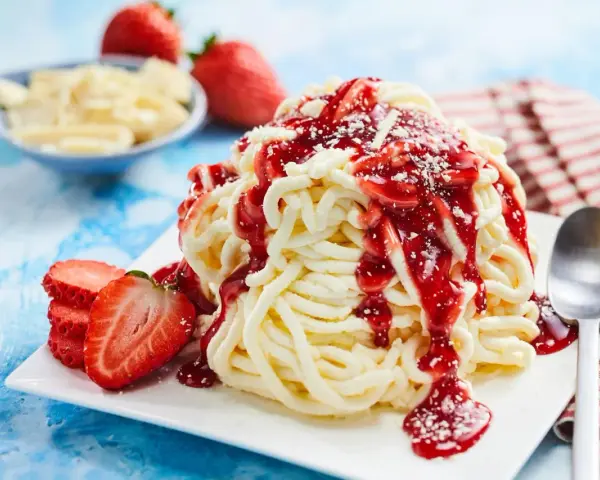 Ein köstliches Spaghetti-Eis-Dessert mit Erdbeersoße und frischen Erdbeeren, bereit zum Genießen.