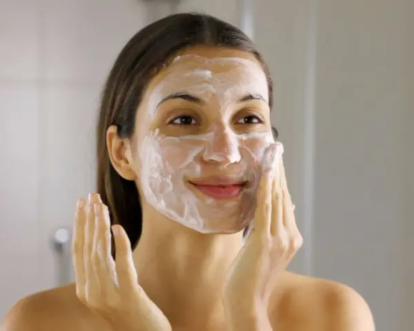 Frau mit Schaum im Gesicht, die ihre Haut reinigt. Ein Schritt im Double Cleansing für reine Haut.