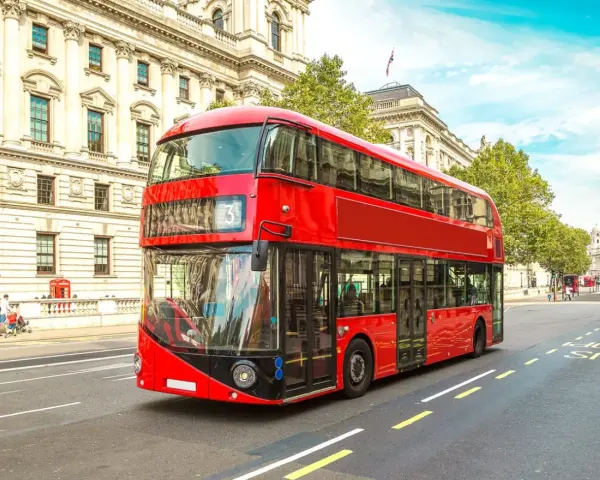 Ikoniczny czerwony autobus piętrowy na ulicy w Londynie, symbol komunikacji miejskiej.