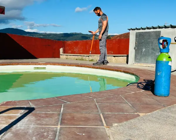 Técnico trabajando en el borde de una piscina, con equipo para impermeabilizar piscina.