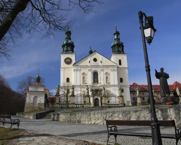 Kalwaria Zebrzydowska zwiedzanie: barokowy kościół z wieżami, kapliczki, ławki i pomnik.