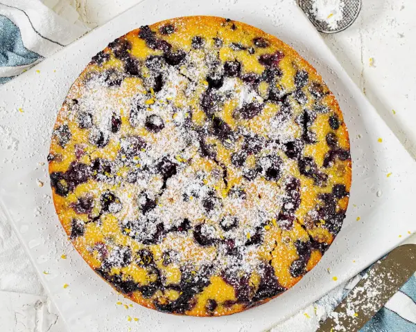 Ein köstlicher glutenfreier Kuchen mit Blaubeeren und Puderzucker bestreut, bereit zum Genießen.