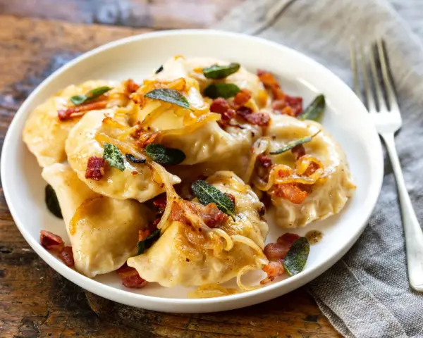 Pyszne pierogi z boczkiem i cebulką, idealne na obiad. Dowiedz się, ile gotować pierogi, by były idealne.