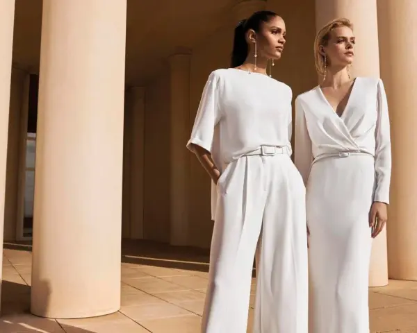 Eleganza senza tempo: come vestirsi ad un matrimonio a 50 anni con pantaloni palazzo e abito longuette in bianco.