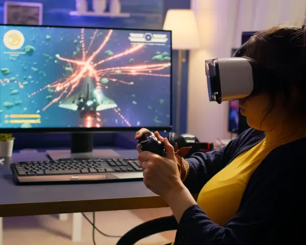 Kobieta w goglach VR gra w kosmiczną strzelankę, testując swoje umiejętności w ramach studiów game design.
