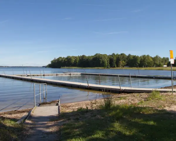 Bryggor vid Hampetorp camping. Solig dag med klarblå himmel över sjön.