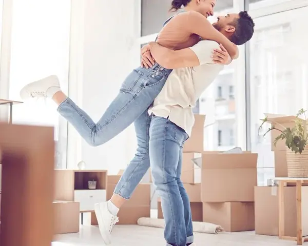 Glückliches Paar umarmt sich in einem neuen Zuhause voller Umzugskartons. Ein aufregender Moment, wann zusammenziehen!
