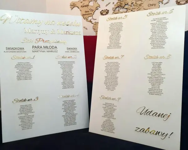 Jak przygotować stylowy plan stołów na lustrze lub szkle akrylowym: złote napisy z listą gości na eleganckim planie weselnym.