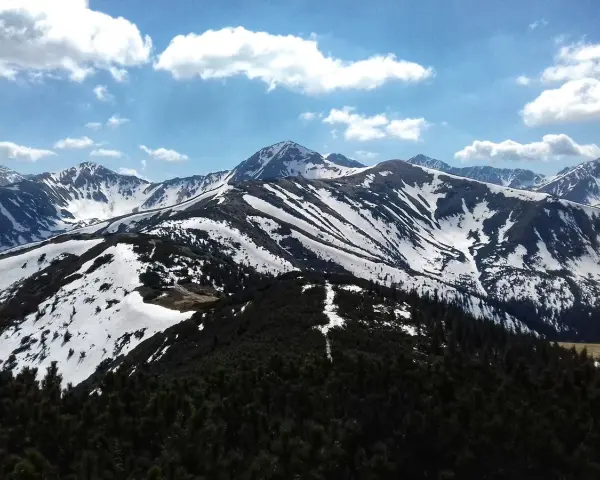 Majestatyczne Tatry w kwietniu, pokryte śniegiem szczyty i zielone lasy.