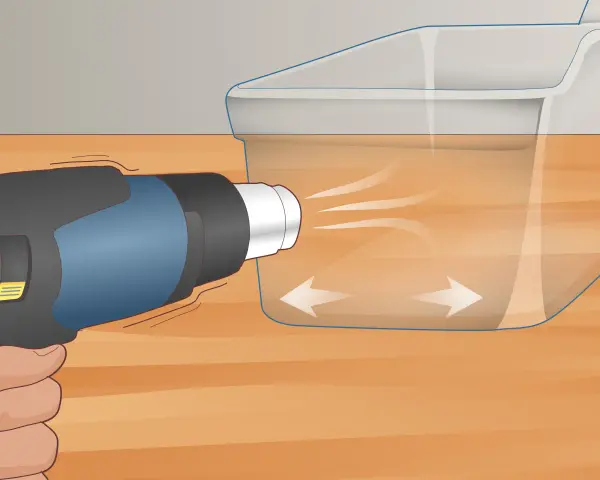 A heat gun is used on low setting to gently warm a scratched plexiglass surface, showing how to get scratches out of plexiglass.