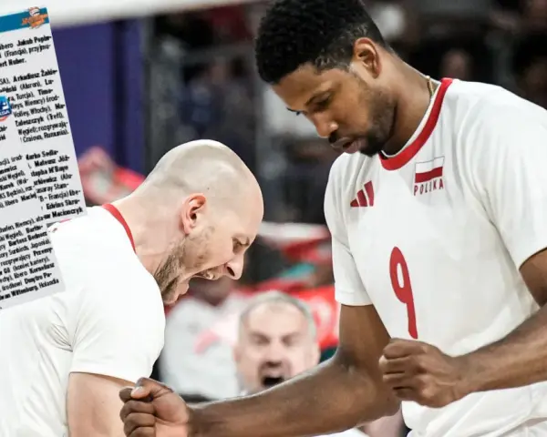 Daniel Stępień, siatkarz w białej koszulce z numerem 9 i godłem Polski, świętuje z kolegą z drużyny.