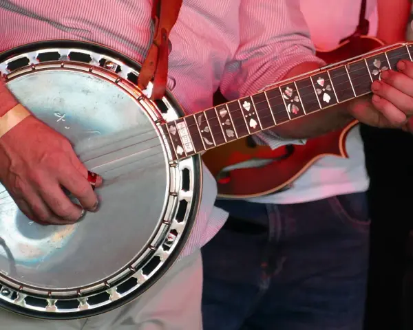 Ein Mann spielt ein Banjo, ein Saiteninstrument mit einem runden Korpus und einem langen Hals.
