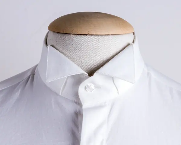 Dettaglio di una camicia bianca su un manichino, che mostra i diversi tipi di colletto camicia.