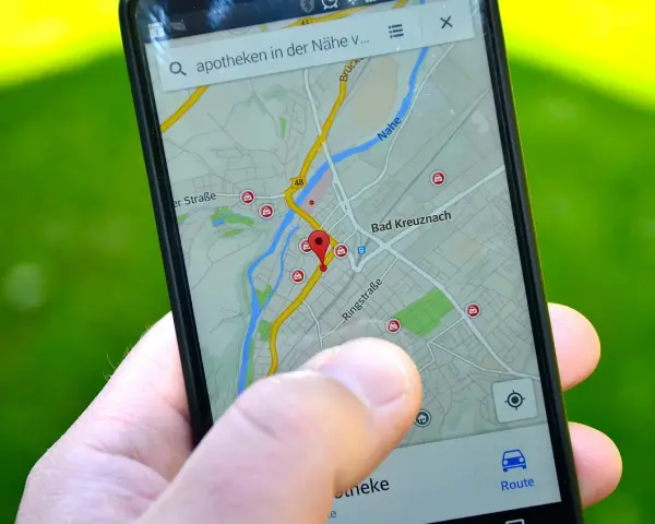 Palec wskazuje na mapę GPS w telefonie, szukając apteki w pobliżu. W samochodzie taka nawigacja to podstawa.