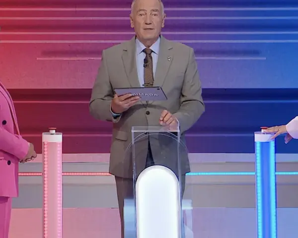Prowadzący Familiady z tabliczką "Miliada" i dwie uczestniczki w różowych strojach. Zastanawiają się, co zmieniamy podczas jazdy samochodem.