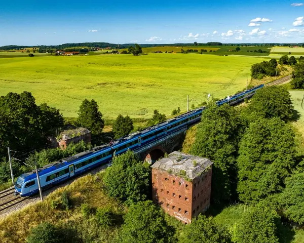 Pociąg mknie przez zielone pola, mijając stare forty. Idealny sposób, by dowiedzieć się, gdzie na Mazury pociągiem.