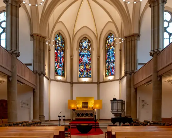 Festlicher evangelischer Gottesdienst am Heiligabend in einer Kirche mit Buntglasfenstern und Holzbänken.