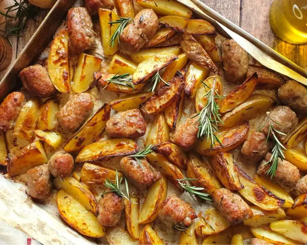 Salsiccia e patate al forno, dorate e profumate al rosmarino, pronte per essere gustate.