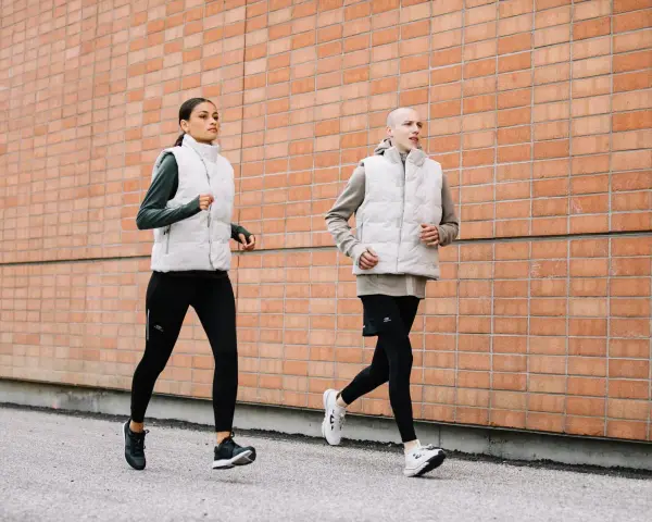 Coppia corre lungo un muro di mattoni. Ottimi consigli per correre in coppia, con abbigliamento tecnico.