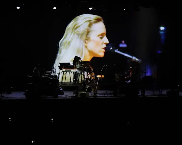 Agnes Obel na ekranie i zespół na scenie podczas koncertu.
