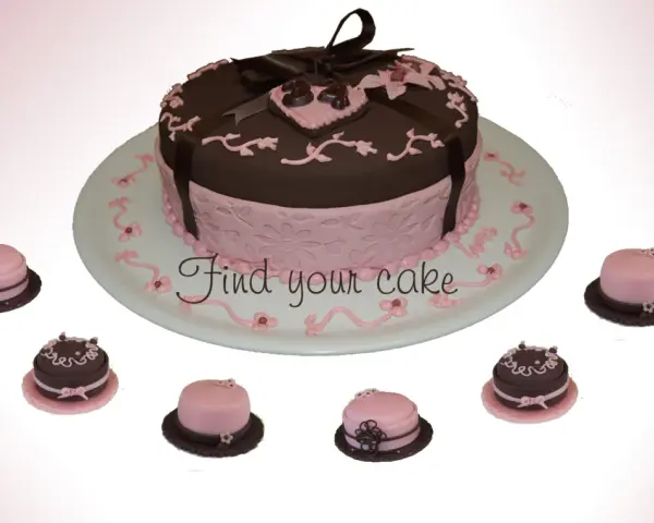 Torta centrale marrone e rosa con decorazioni in pasta di zucchero, circondata da mini-torte.