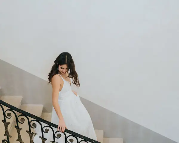 Une mariée descend un escalier, sa robe blanche fluide. Un moment clé pour comment choisir sa robe de mariée.
