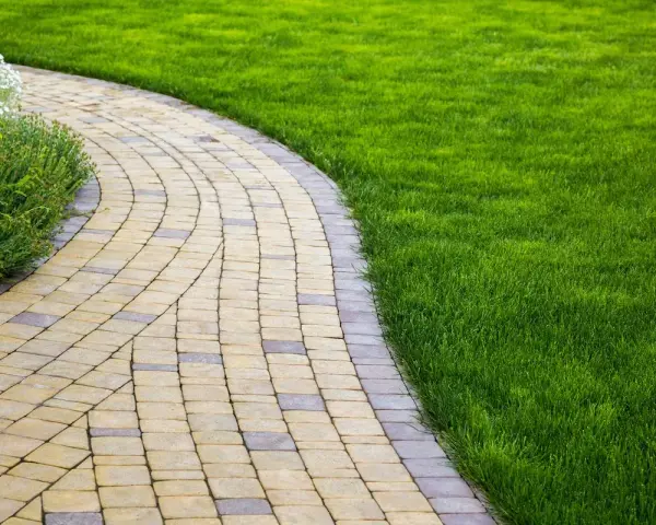 Vialetti giardino fai da te in pietra, con prato verde curato e aiuole fiorite.