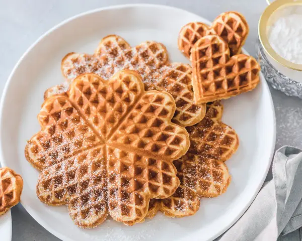 Herzförmige Waffeln mit Puderzucker bestäubt, ein Genuss für Kinder.