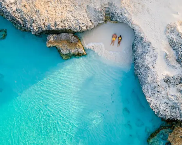 Para na plaży na wyspie Aruba, otoczeni turkusową wodą i skalistymi klifami. Idealne miejsce na relaks.