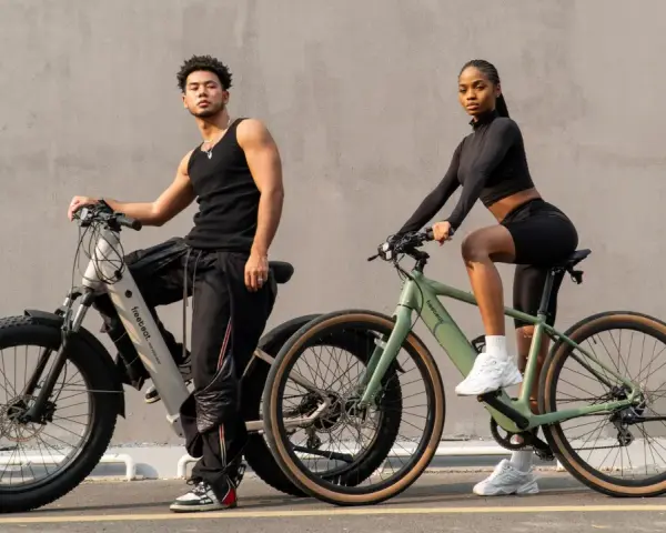 A man and woman pose with their electric hybrid bikes, showcasing a blend of urban style and off-road capability.