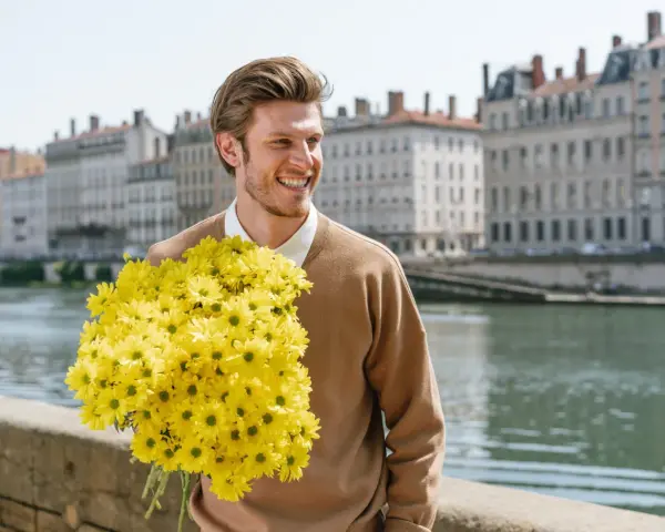 Hombre sonriente con un gran ramo de flores amarillas, quizás buscando el significado de flores para hombres.