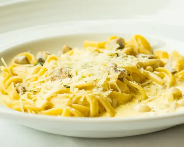 Pyszny makaron z grzybami w kremowym sosie, posypany parmezanem. Idealny przepis na obiad.