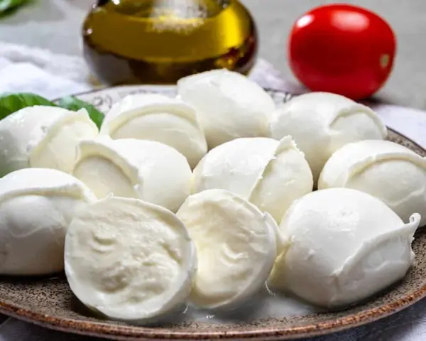 Frische Mozzarellakugeln auf einem Teller, garniert mit Basilikum. Perfekt für eine leichte Mahlzeit während der Schwangerschaft.