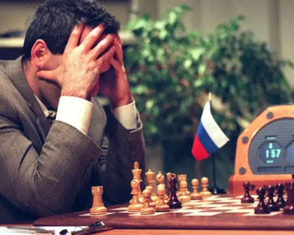 Garry Kasparov, le visage dans les mains, face à Deep Blue. L'horloge d'échecs affiche 1:57 et 1:56.