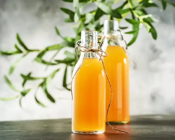 Dwie butelki z domową kombuchą, idealne do nauki jak zrobić grzyb kombucha.