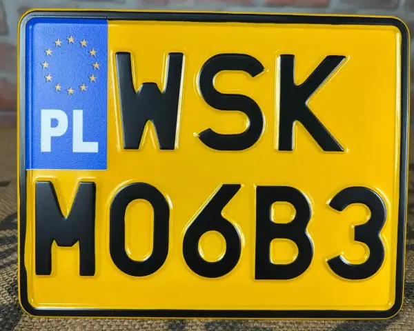 Żółta tablica rejestracyjna z czarnymi znakami "WSK MO6B3" i niebieskim polem "PL" z gwiazdkami UE.