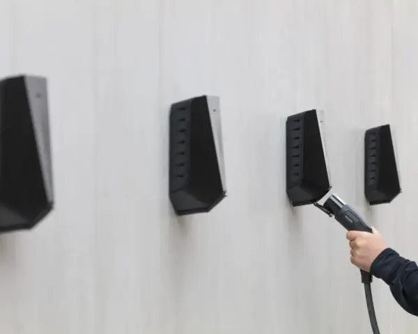 En hand håller en laddkabel mot en Easee laddbox. Ett potentiellt Easee laddbox problem kan vara att kabeln inte kopplas in korrekt.
