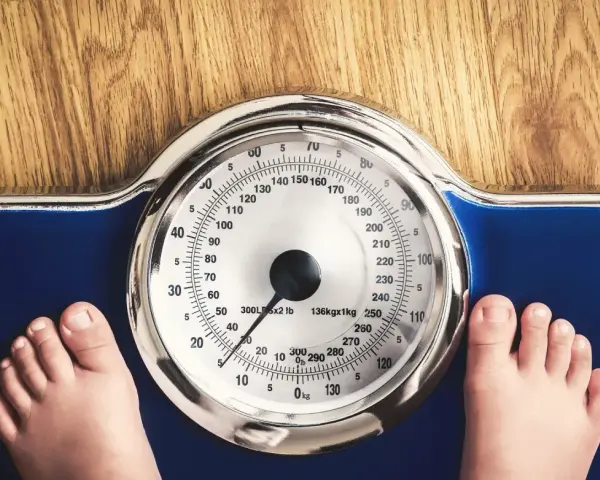 Dziecko staje na wadze. Zastanawiasz się, ile powinien ważyć 14 latek przy wzroście 170 cm?