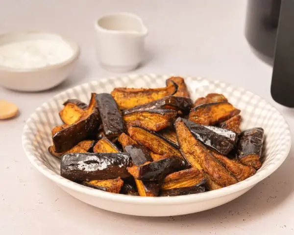 Berenjenas en freidora de aire, doradas y crujientes, listas para disfrutar con un dip cremoso.
