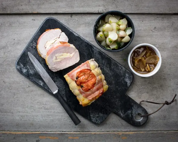 Un délicieux roti de porc Orloff, tranché et garni, accompagné de légumes et d'une sauce onctueuse.