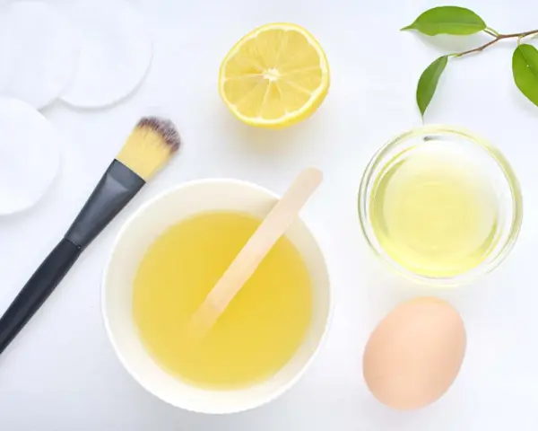 Ingredientes para una mascarilla casera para el pelo: limón, huevo, aceite y aplicador.