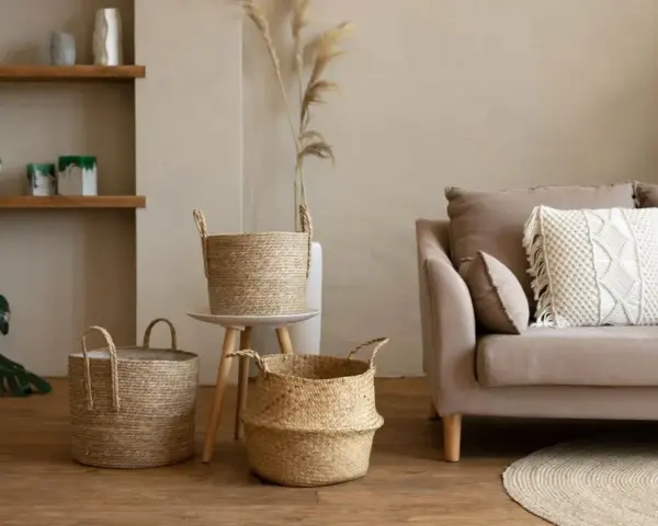 Przytulny salon w stylu boho: plecione kosze, beżowa kanapa z makramową poduszką i suszone trawy.