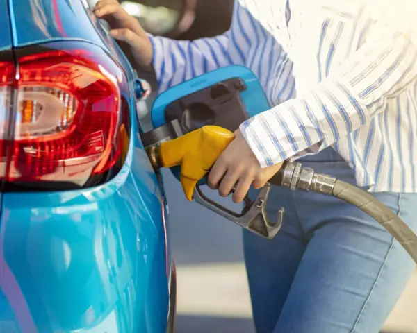 Persona fa rifornimento alla sua auto blu, pensando a come pneumatici con bassa resistenza al rotolamento migliorano l'efficienza.