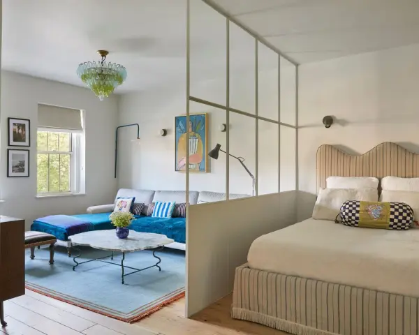 Soluzione creativa per come dividere una camera in due con una sola finestra: zona giorno e zona notte separate da un pannello vetrato.