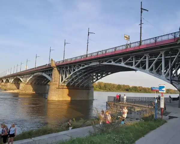Most Poniatowskiego nad Wisłą, z ludźmi spacerującymi po bulwarach i podziwiającymi architekturę.