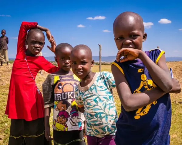 Dzieci z plemienia Masajów, żyjących w Kenii i Tanzanii, pozują do zdjęcia na tle sawanny.